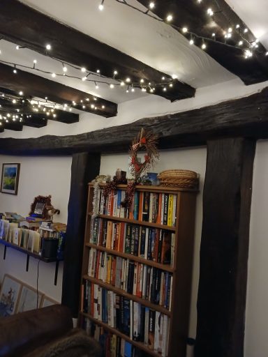 Cosy room with wooden beams, fairy lights, and a bookshelf filled with books.