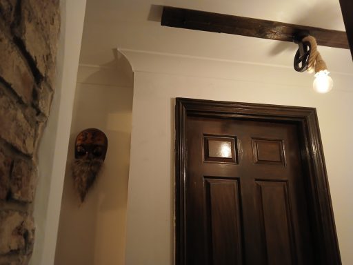 Wooden door with light above, featuring a decorative mask on the wall.