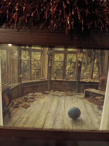 A dimly lit, messy room with a blue ball on the wooden floor and large windows.