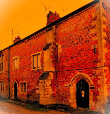 Red brick building with multiple windows and a stone archway entrance, set against an orange backdrop.